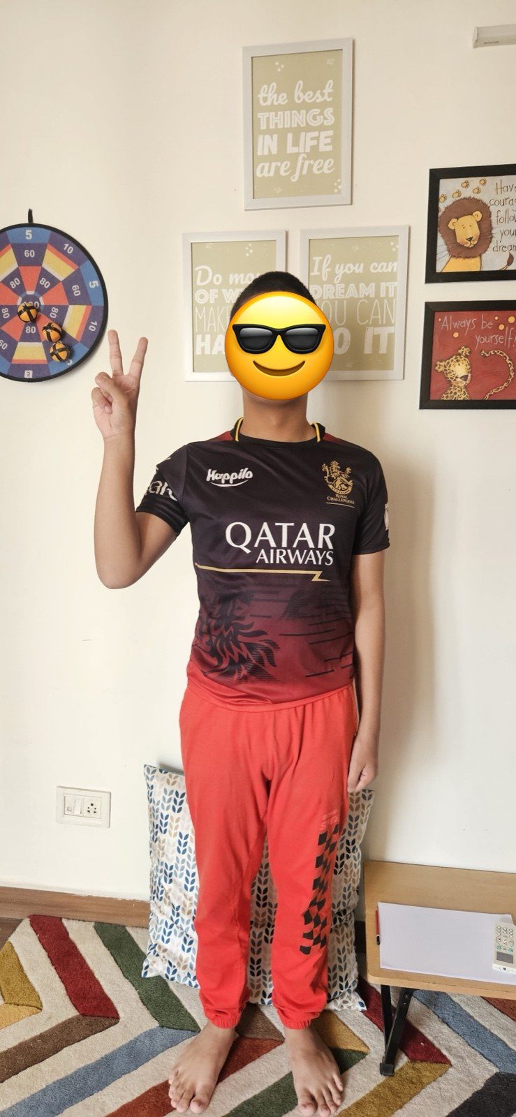 A confident teenager making a peace sign indoors &mdash; face covered with an emoji for privacy