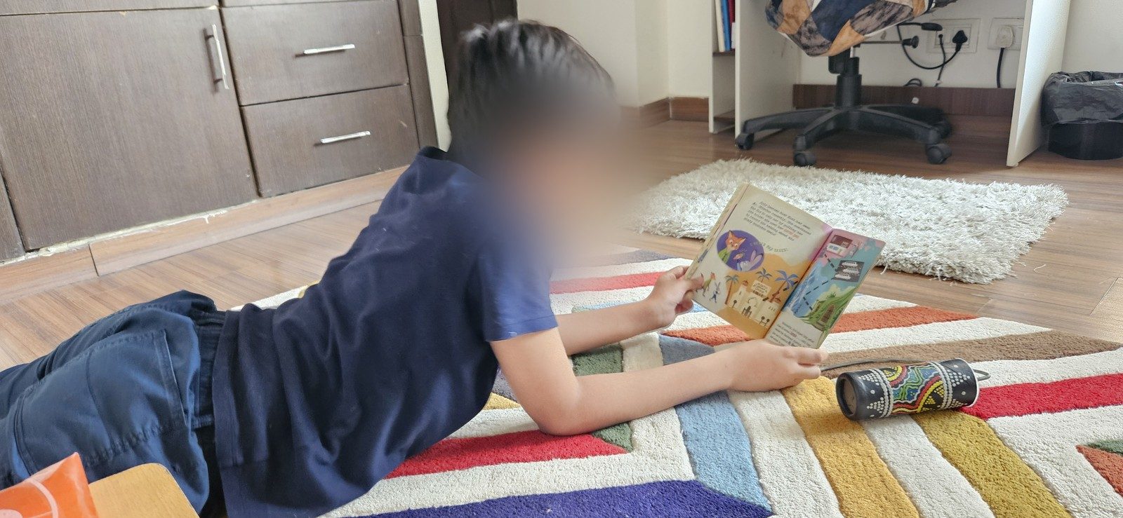 A child reading on a colourful rug in Prachi’s therapy room, face softened for privacy