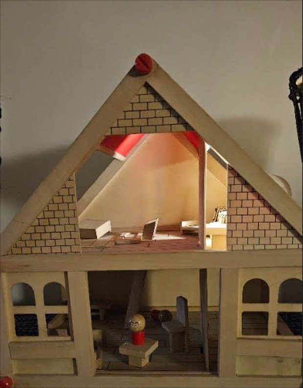 The wooden doll house in Prachi’s therapy room, its rooms furnished and a small figure standing inside