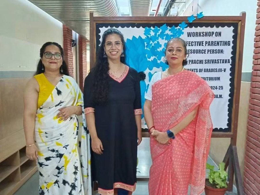 Prachi Srivastava with two school staff members beside an Effective Parenting workshop board