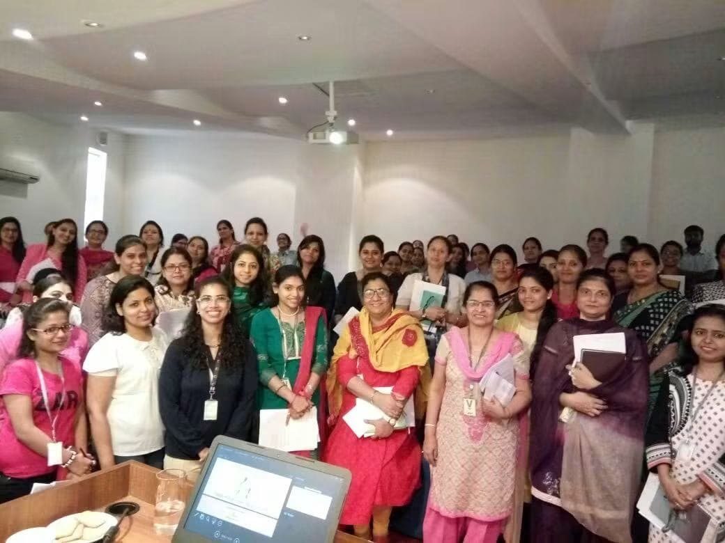 A large cohort of smiling teachers with Prachi after a training session